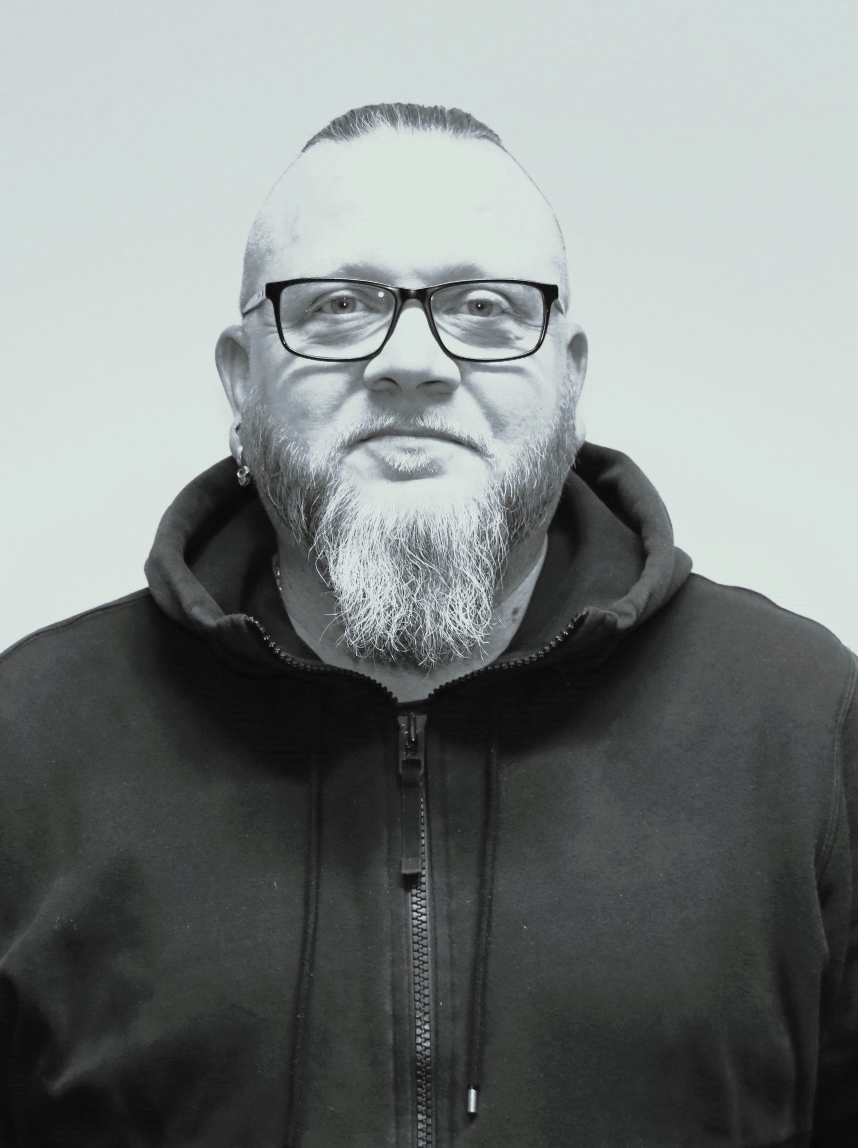 Ett svartvitt foto av en man med glasögon och skägg.