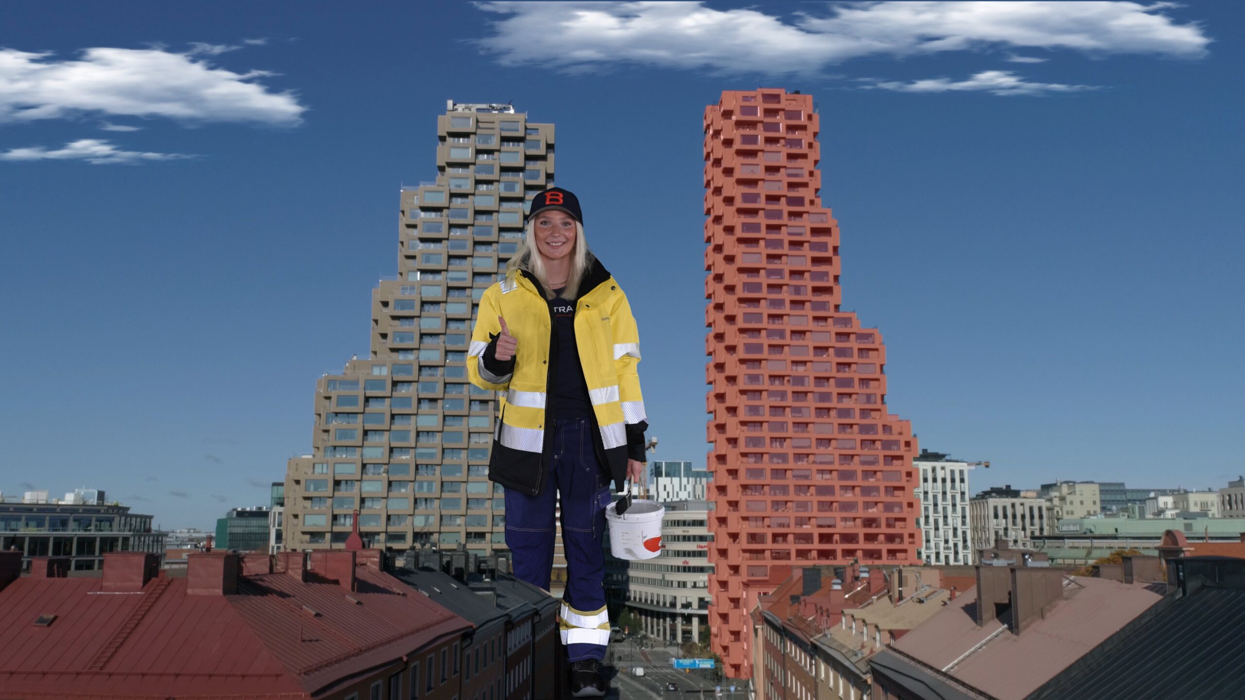 En kvinna i en gul jacka som står framför två höga byggnad.
