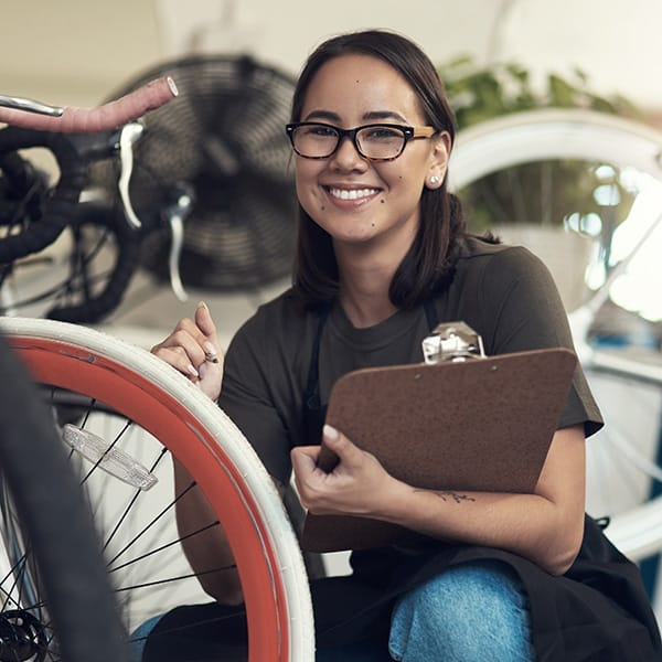 En kvinna som håller en urklipp bredvid en cykel.
