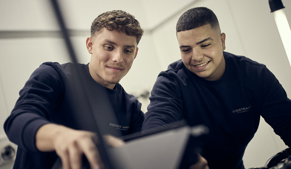Två unga män som arbetar på en bärbar dator i en verkstad.