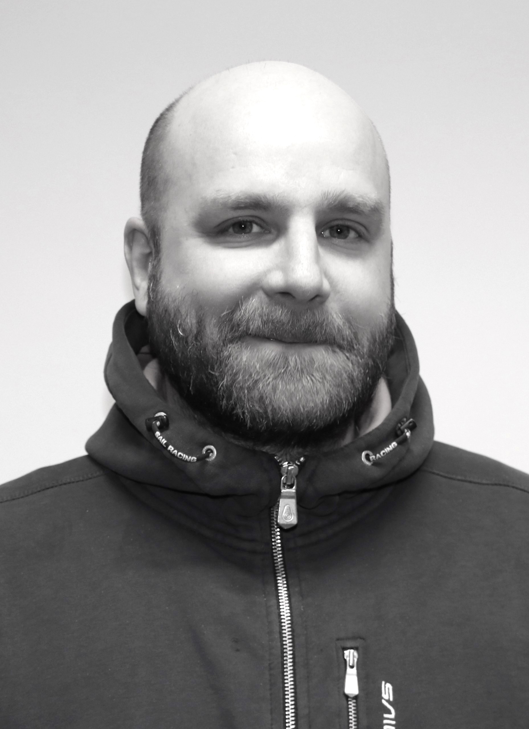 Ett svartvitt foto av en skallig man som bär en hoodie.